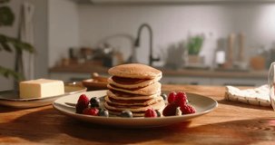 Visually pleasing arrangement of pancakes with berries and powdered sugar. No people, advertisement. Kitchen-themed video, joy of healthy eating recipes for family, recipes for every day and weekends.