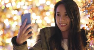 Woman taking selfie on mobile phone with Christmas tree decoration