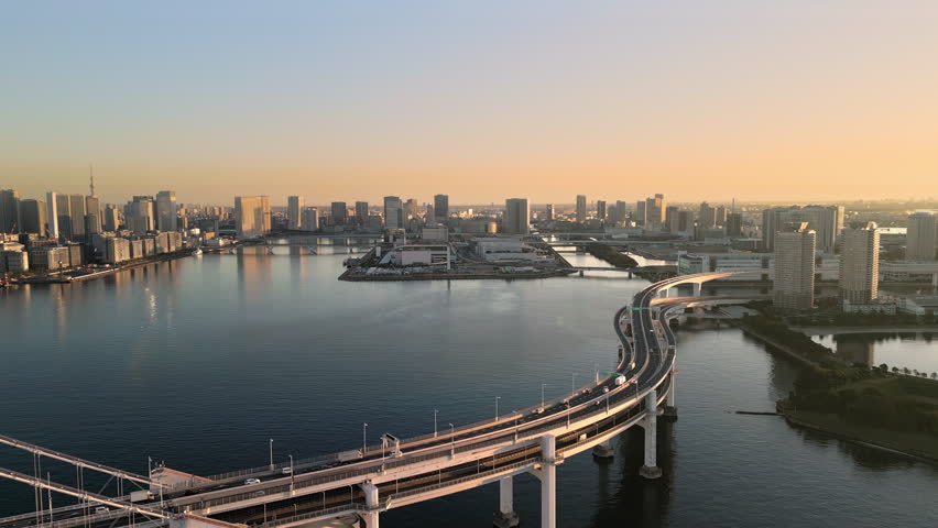 tokyo city rainbow bridge aerial view drone,traffic on highway street crossing the sea bay kotoku district in the background from odaiba ward at sunrise dawn