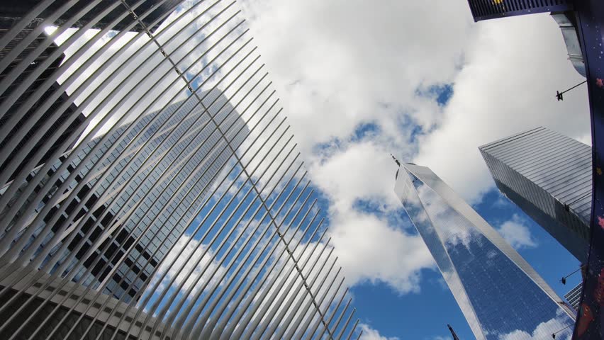 One World Trade Center and a part or World Trade Center Hub. The station house was opened as the World Trade Center Transportation Hub. Clouds and blue sky reflecting on the glass skyscraper Royalty-Free Stock Footage #3401556673