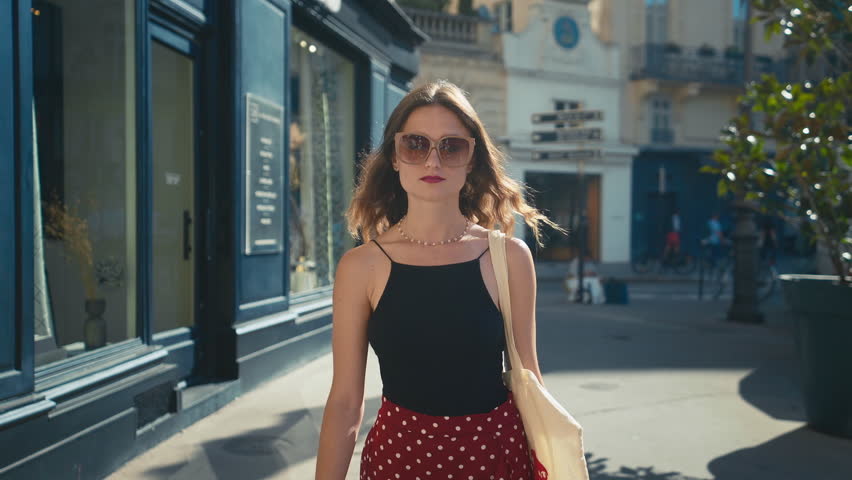 Stylish Young Woman texts back on the phone exploring Sunlit European Streets