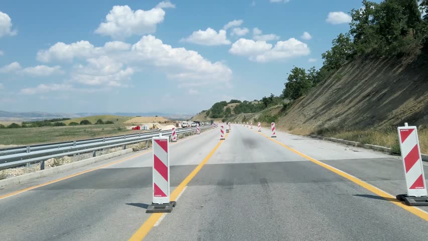 Pov driving on highway road with warning sign hinders in a hazard zone during construction road works