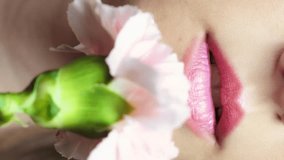 Closeup slow motion vertical video of female with pink carnation flower near face. Macro footage of woman with natural lips beauty makeup
 - Powered by Shutterstock - Get 15% off with code: PIKWIZARD15