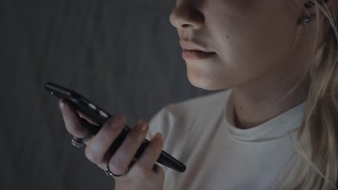 girl using smart phone voice recognition, dictates thoughts, voice dialing message at night evening home student model young. Communication while coronavirus quarantine on home isolation