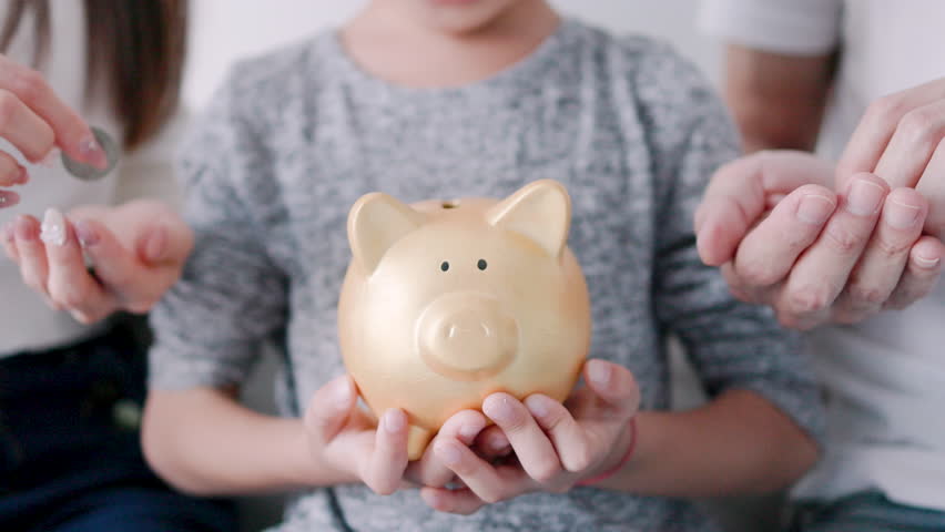 happy family hands holding piggy bank. kid and parents put coins  into piggy bank Royalty-Free Stock Footage #3401719523