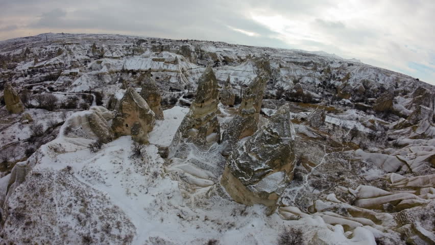 Aerial Shot Of Natural Rock Hoodoos On Snowy Volcanic Landscape Under Cloudy Sky - Cappadocia, Turkey