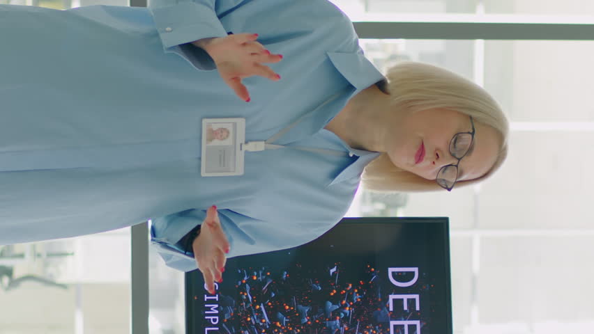 Vertical shot of female professor lecturing students on psychology topic with help of modern technology such as display and remote controller
