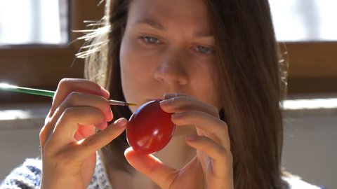 Girl paints red easter egg
