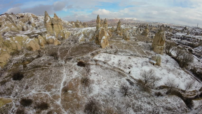 Aerial View Of Historic Fairy Chimneys On Snowy Volcanic Land Under Cloudy Sky - Cappadocia, Turkey