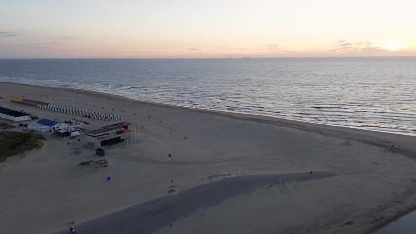 Netherlands. Beautiful flight in summer over the beach in Katwijk aan Zee. People are resting near the sea. Houses for tourists. Beautiful sunset over the North Sea.