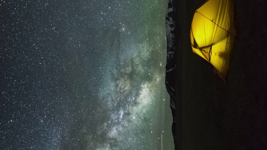 Cumulative Time Lapse Of Night Starry Sky with Star Trails over Yellow Glowing Tent. Vertical Video