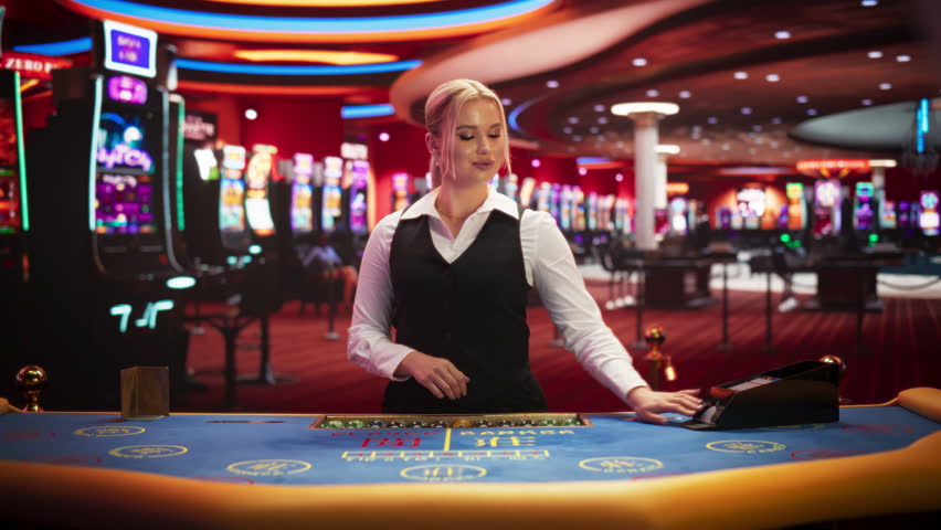 Professional Female Croupier in Casino Dealing Playing Cards on a Baccarat Table. Beautiful Dealer of a Live Online Casino Reveals Winning Results of the Card Game Bets, Looking at Camera. Static Shot Royalty-Free Stock Footage #3401955023