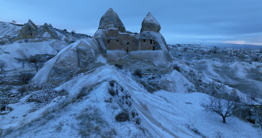 Aerial Forward Beautiful View Of Ancient Cave Houses During Snowy Weather Under Cloudy Sky - Cappadocia, Turkey