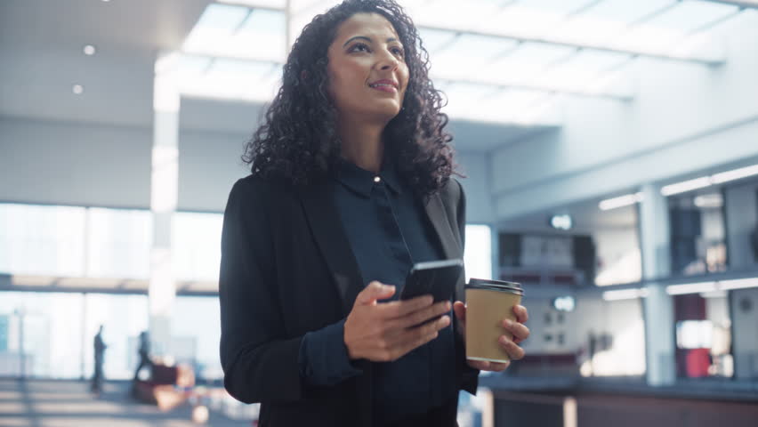 Portrait of a Happy Multiethnic Woman Texting on her Smartphone and Walking in Corporate Office. Confident Female Marketing Manager Checking Social Media Trends and Staying Updated - Powered by Shutterstock - Get 15% off with code: PIKWIZARD15
