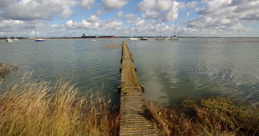 extra wide mid shot of a long wooden jetty with flooding debris on top. Taken at Ashlett creek sailing club in the Solent, Southampton Royalty-Free Stock Footage #3402112339
