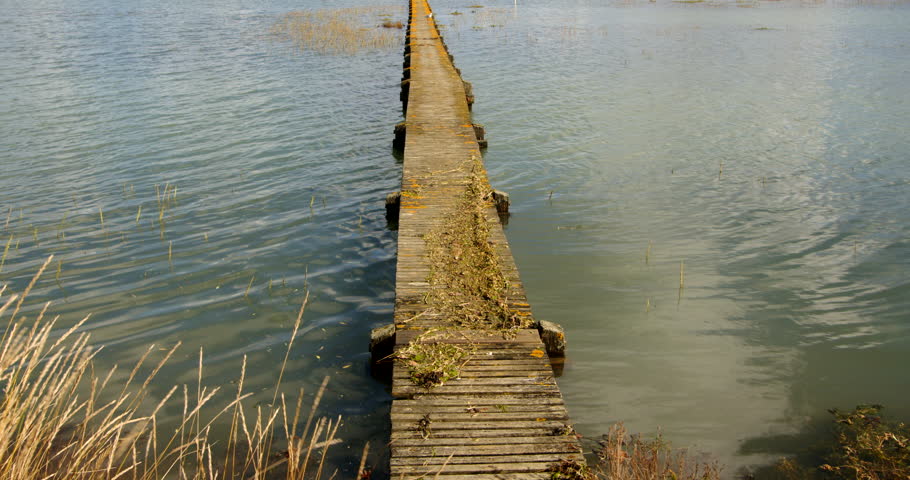 wide mid shot of a long wooden jetty with flooding debris on top. Taken at Ashlett creek sailing club in the Solent, Southampton Royalty-Free Stock Footage #3402116429
