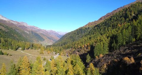 Autumn color road, Cinema 4k aerial view between colorful fall mountains, revealing a asphalt road, on a sunny october day, on nufenen pass, in ticino, switzerland