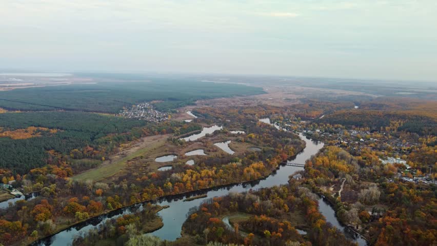 Autumn aerial tilt down view on river dale with forest on riverbanks. Hills of Siverskyi Donets River valley in Ukraine