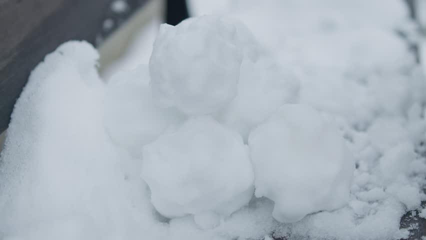Slowmotion closeup of grabing and removing pile of snowballs with black gloves