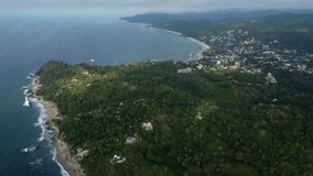 Vertical video of Panning from coastal city along tropical dense forest hills to beach