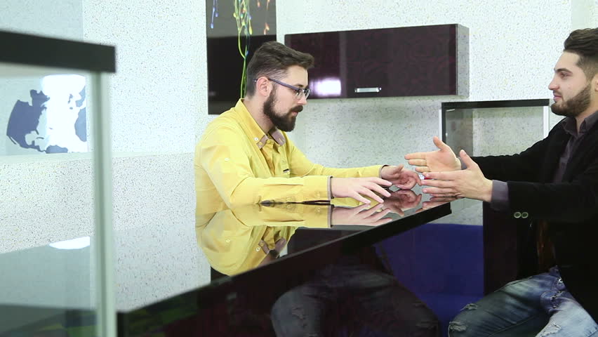 Portrait of two young handsome caucasian business man using smartphone talking to each other