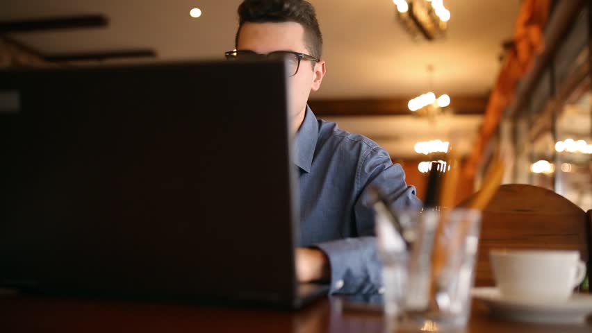 Handsome freelancer businessman in glasses diligently working on laptop in cafe is constantly distracting by annoying smartphone advertising notifications and messages. Business multitasking concept | Shutterstock HD Video #34024369