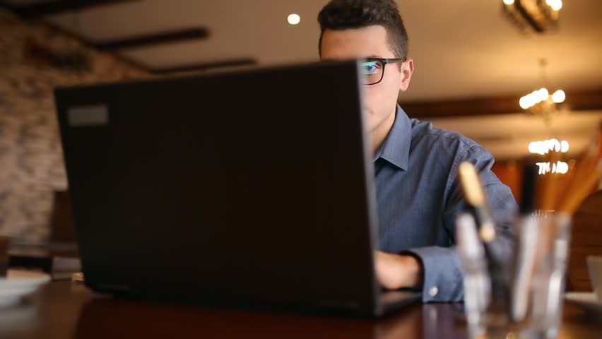 Hurried handsome young male businessman in glasses working under pressure on laptop, many wireless communication devices, responding to mail messages and taking notes. Multitasking telecommuting Royalty-Free Stock Footage #34024375