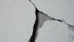Closeup, Old concrete wall background with large crack.Grey cement wall surface with large damage. Video macro.