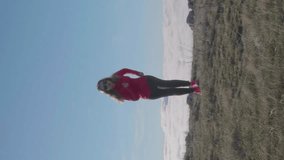 Young caucasian woman in sunglasses with long hairs is jogging above clouds. Vertical Video