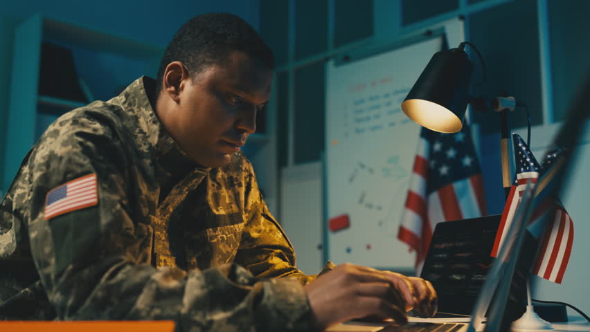 African American U.S. army officer works on laptop, controls military operation