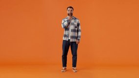 Bearded pensive guy in plaid shirt, holding hand on face, reasoning over problem, smiling and suddenly looking at camera with happy look, finding solution isolated on orange background - Powered by Shutterstock - Get 15% off with code: PIKWIZARD15