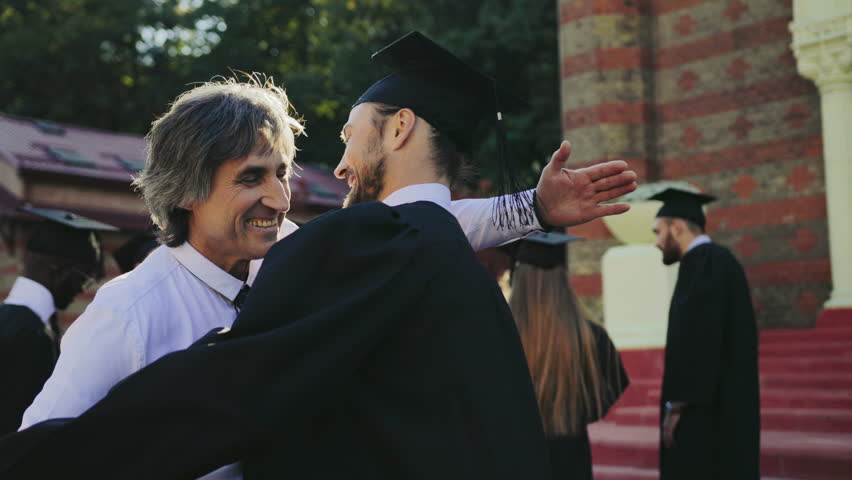 Handsome male graduate hugging with his father, dad congratulating his son with a graduation from University. Outdoor Royalty-Free Stock Footage #34025731