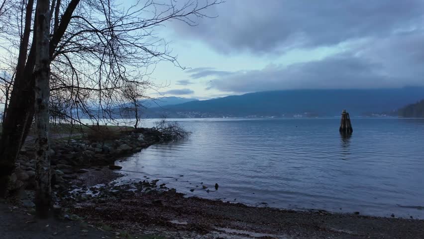 Rocky Shore by the Ocean in a city park. Sunset Sky. Barnet Marine Park, Burnaby, Vancouver, BC, Canada. Slow motion