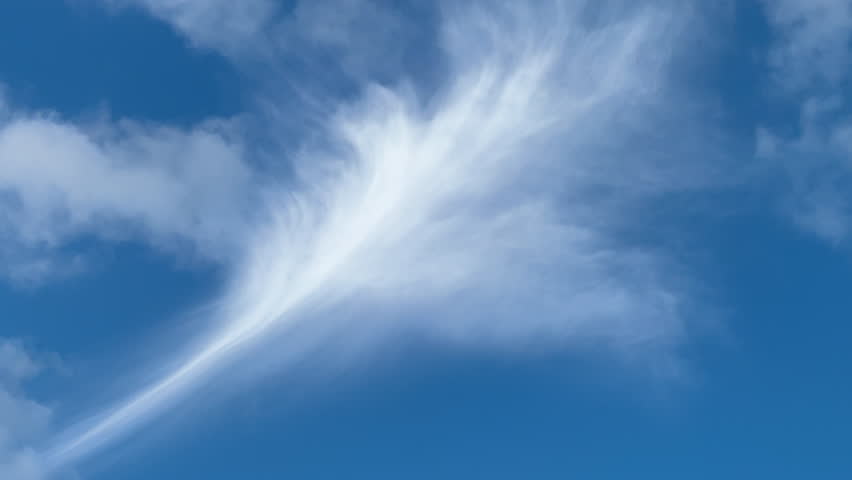 Cirrus cloud with a flowery shape above faster-moving puffy clouds in blue sky. Late afternoon at winter solstice in southwest Florida. Royalty-Free Stock Footage #3402616607