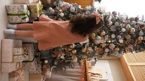 Little girl decorates Christmas tree. Happy cozy family holidays. Vertical video