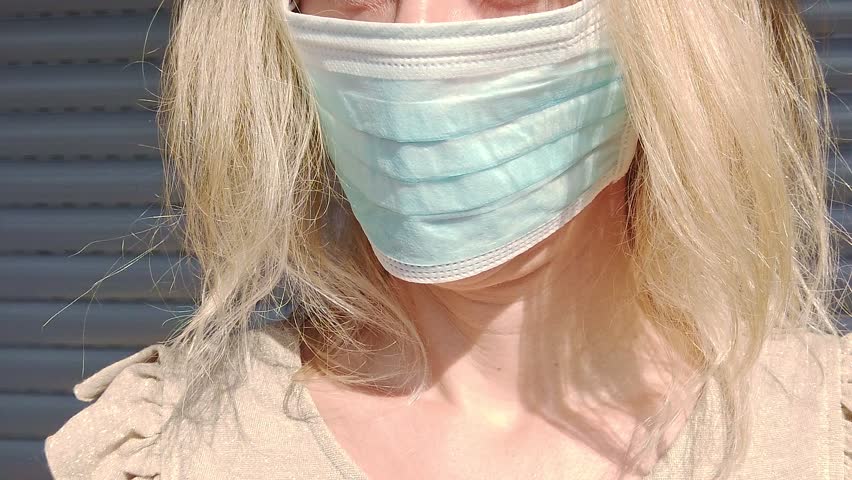 SLOW MOTION: side view close up of a blonde girl with a face mask. Concept of the epidemic outbreak, quarantine for public health care and outbreak of the corona-virus Royalty-Free Stock Footage #3402666143