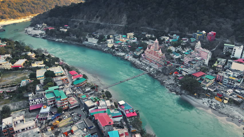 Drone shot of Rishikesh City. Aerial view of the beautiful holy river Ganga, Lakshman Jhula bridge, and Tera Manzil Temple, Trimbakeshwar in Rishikesh. Holy town and travel destination in India. Royalty-Free Stock Footage #3402793391