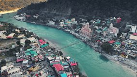 Drone shot of Rishikesh City. Aerial view of the beautiful holy river Ganga, Lakshman Jhula bridge, and Tera Manzil Temple, Trimbakeshwar in Rishikesh. Holy town and travel destination in India.