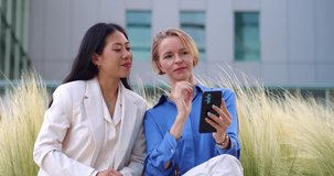 Two young diverse business women making a video call with smartphone in a financial district