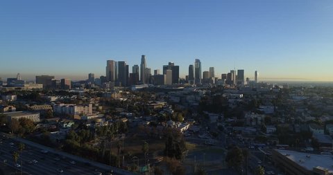 Cinematic aerial drone footage of urban downtown Los Angeles as seen from Echo Park with the city skyline, sky scrapers, freeway and traffic below.