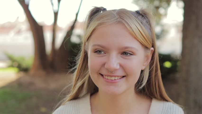 Close up portrait of smiling teenage girl with nose ring sitting in park outdoors. Happy childhood