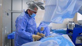 Surgeon performs endoscopic procedure using metal tool. Modern C-arm x-ray machine is above the operational spot. - Powered by Shutterstock - Get 15% off with code: PIKWIZARD15