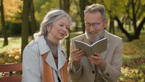 Retired Caucasian couple gray-haired grandparents reading book pension leisure time in autumn park happy old 70s aged loving man husband and wife woman relaxing on bench together retirement outdoors - Powered by Shutterstock - Get 15% off with code: PIKWIZARD15