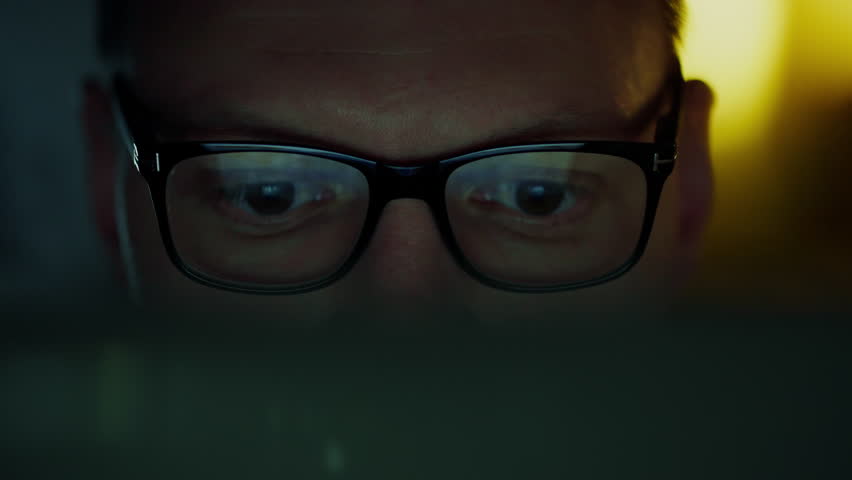 In an office space, lines of code flash on the monitor, reflected in the glasses of an IT specialist immersed in night work. Programmer working intently on laptop laptop using advanced software Royalty-Free Stock Footage #3403143061