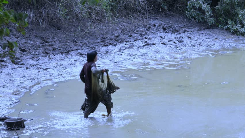 Asian man catches fish by casting a net