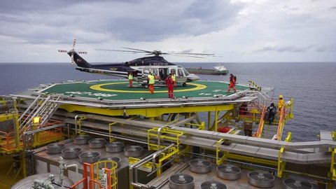 KELANTAN, MALAYSIA - NOVEMBER 16th, 2017 : Unidentified offshore workers get out from Agusta Westland AW 139 helicopter after safely landing on helideck and pick up their luggage to report duties.