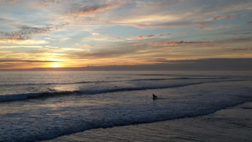 Sunset scene with surfers riding ocean waves at Swamis Reef Surf Park Encinitas California.