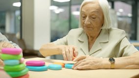Elder woman playing skill games with round pieces in geriatrics