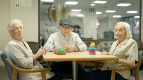 Three senior people looking at camera sitting on a nursing home