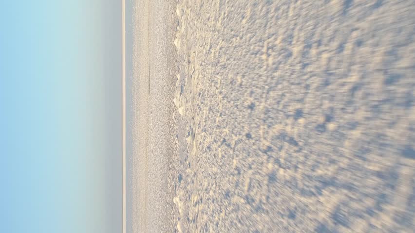 Low angle fast flying over the white salt lake with deposits of salt. First point view mode. Aerial view. Vertical Video